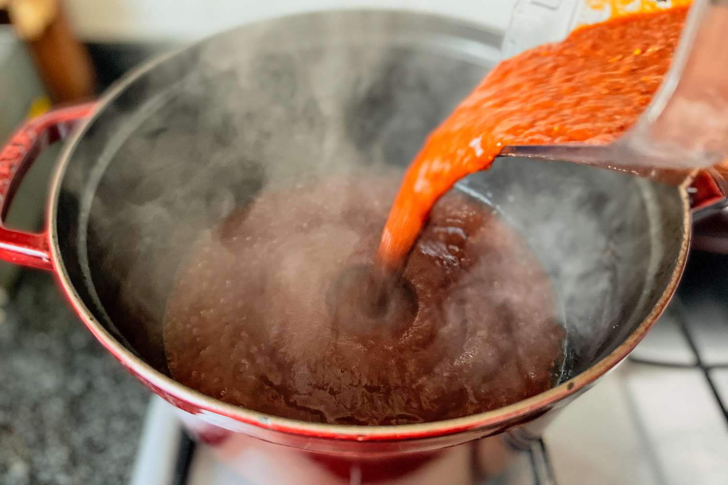 A purée being poured into a Dutch oven