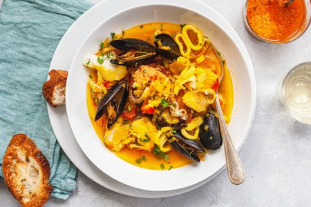 Overhead view of a bowl of bouillabaise and sliced bread.