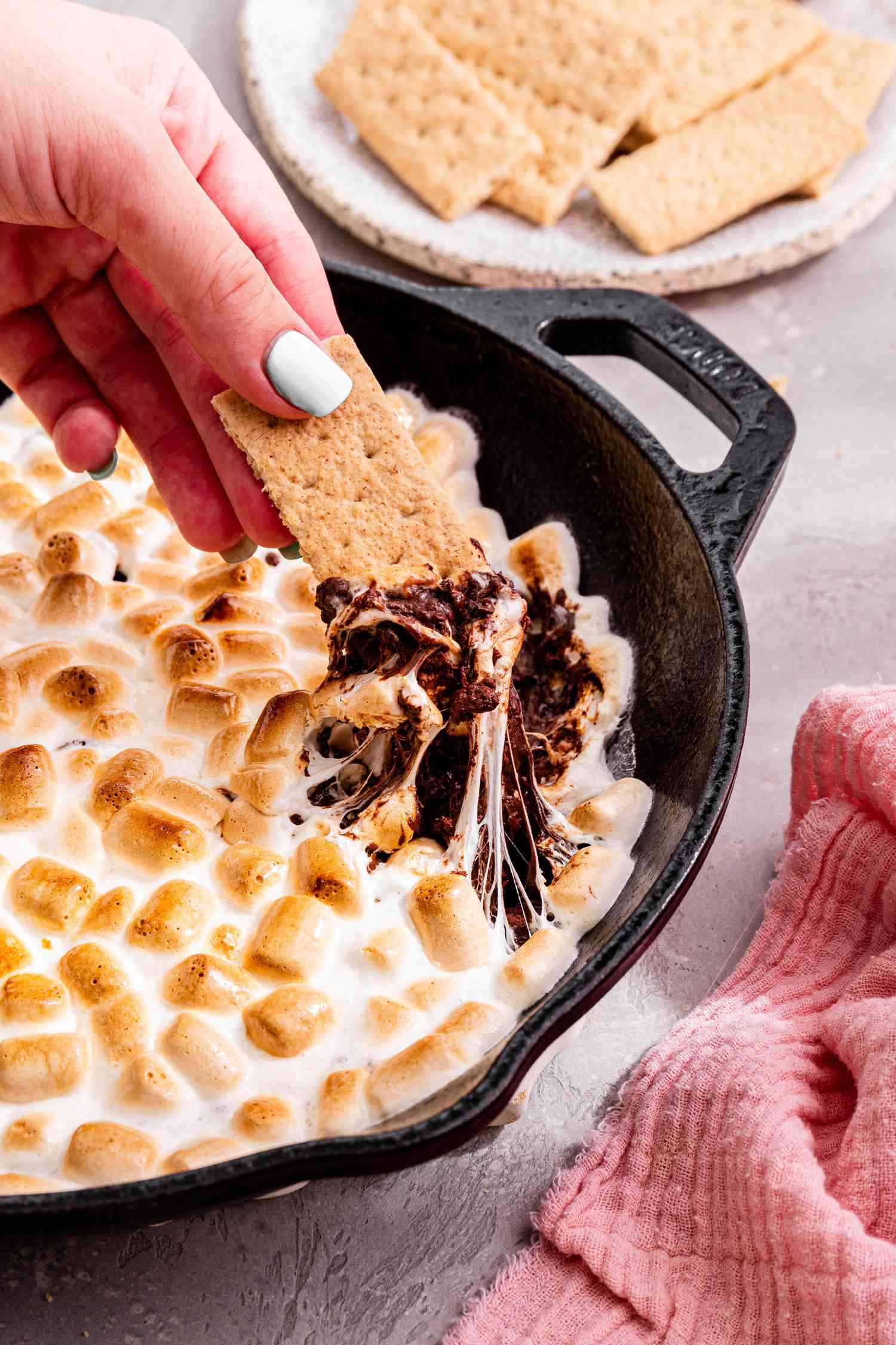 Hand lifting graham cracker with s'mores dip
