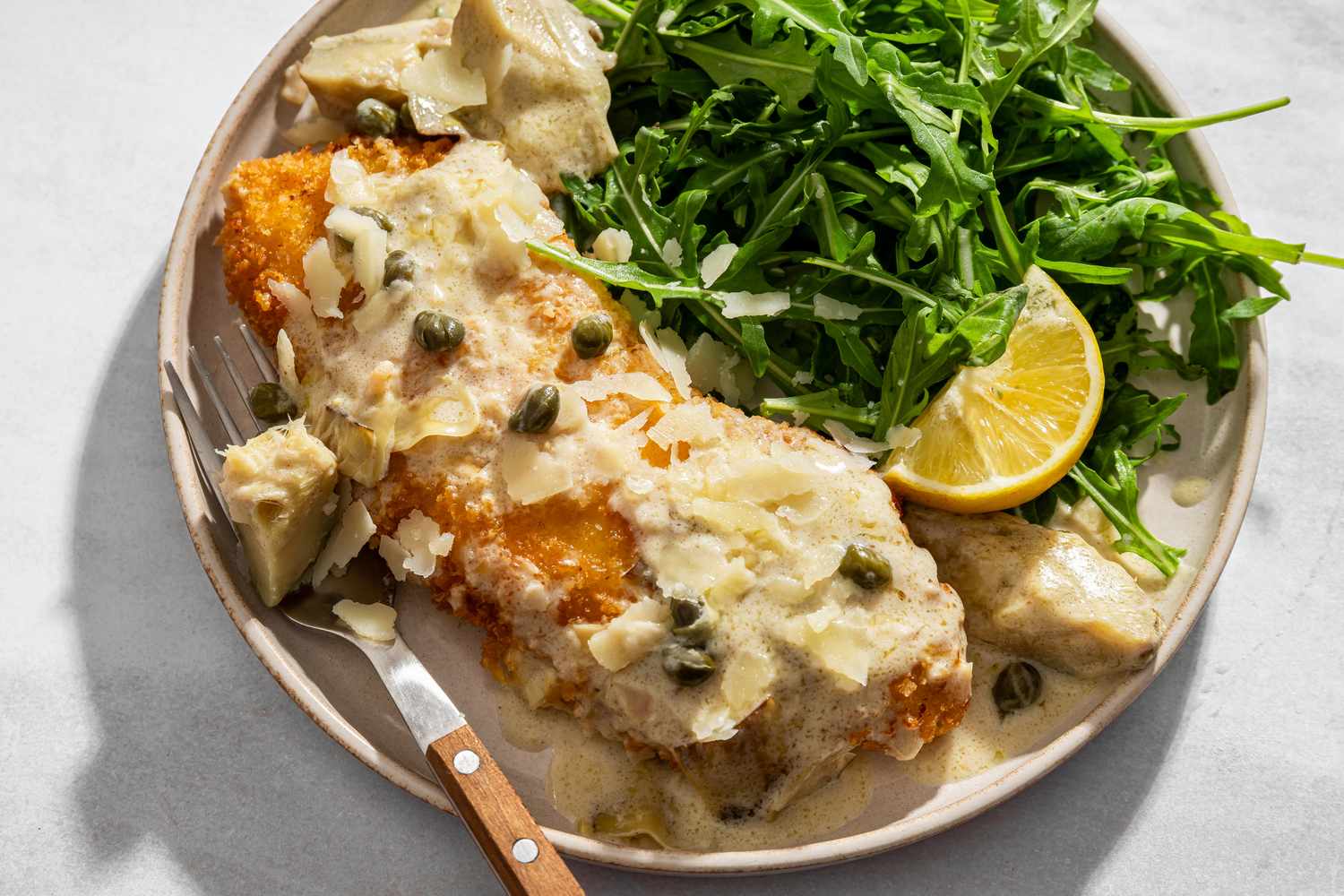 overhead view of a serving of Lemon-Artichoke Chicken Piccata served with arugula