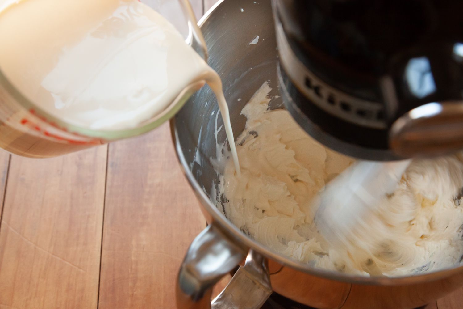 Pouring cream into a stand mixer to make the best whipped cream frosting recipe.