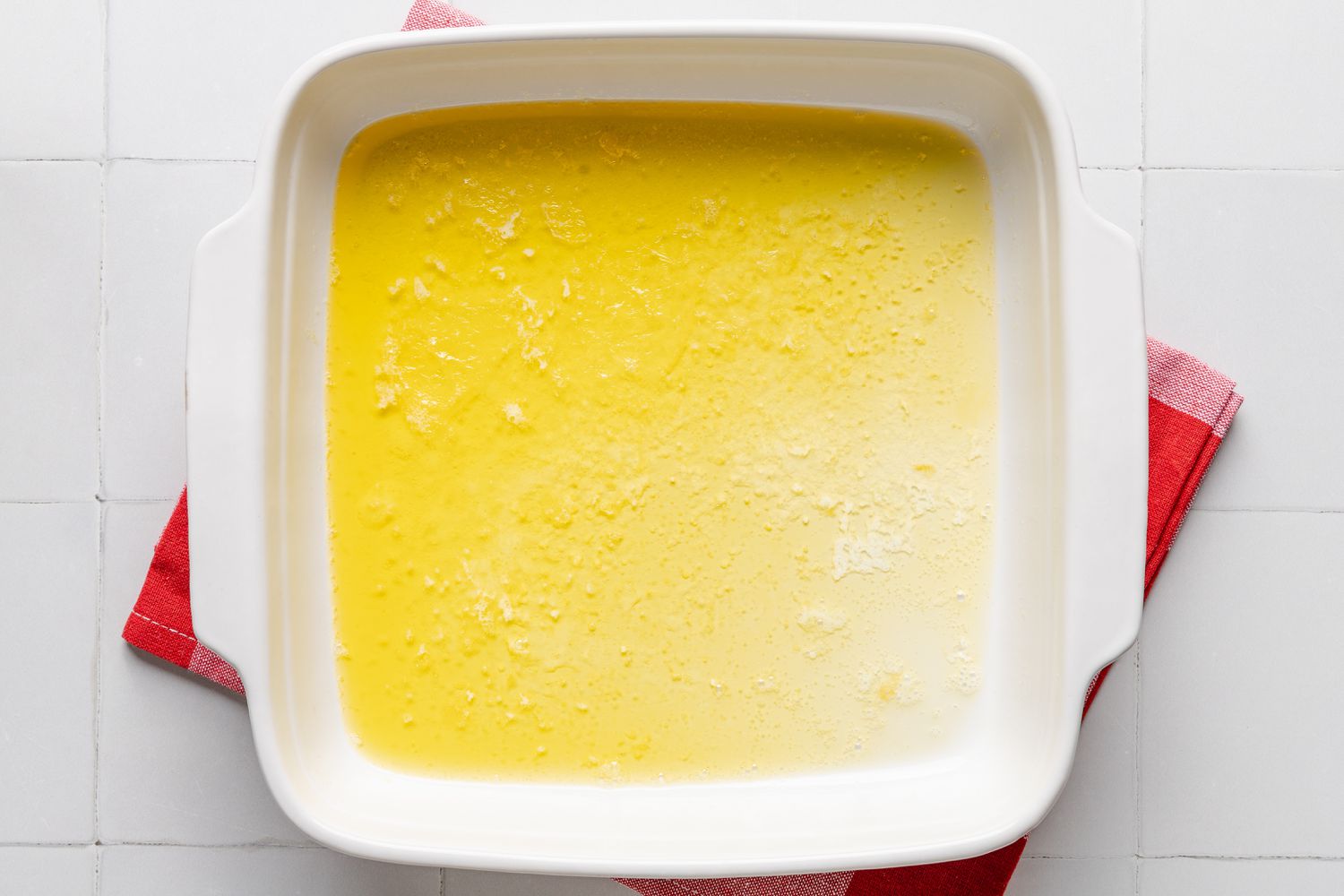 melted butter in a baking pan for butter swim biscuits recipe