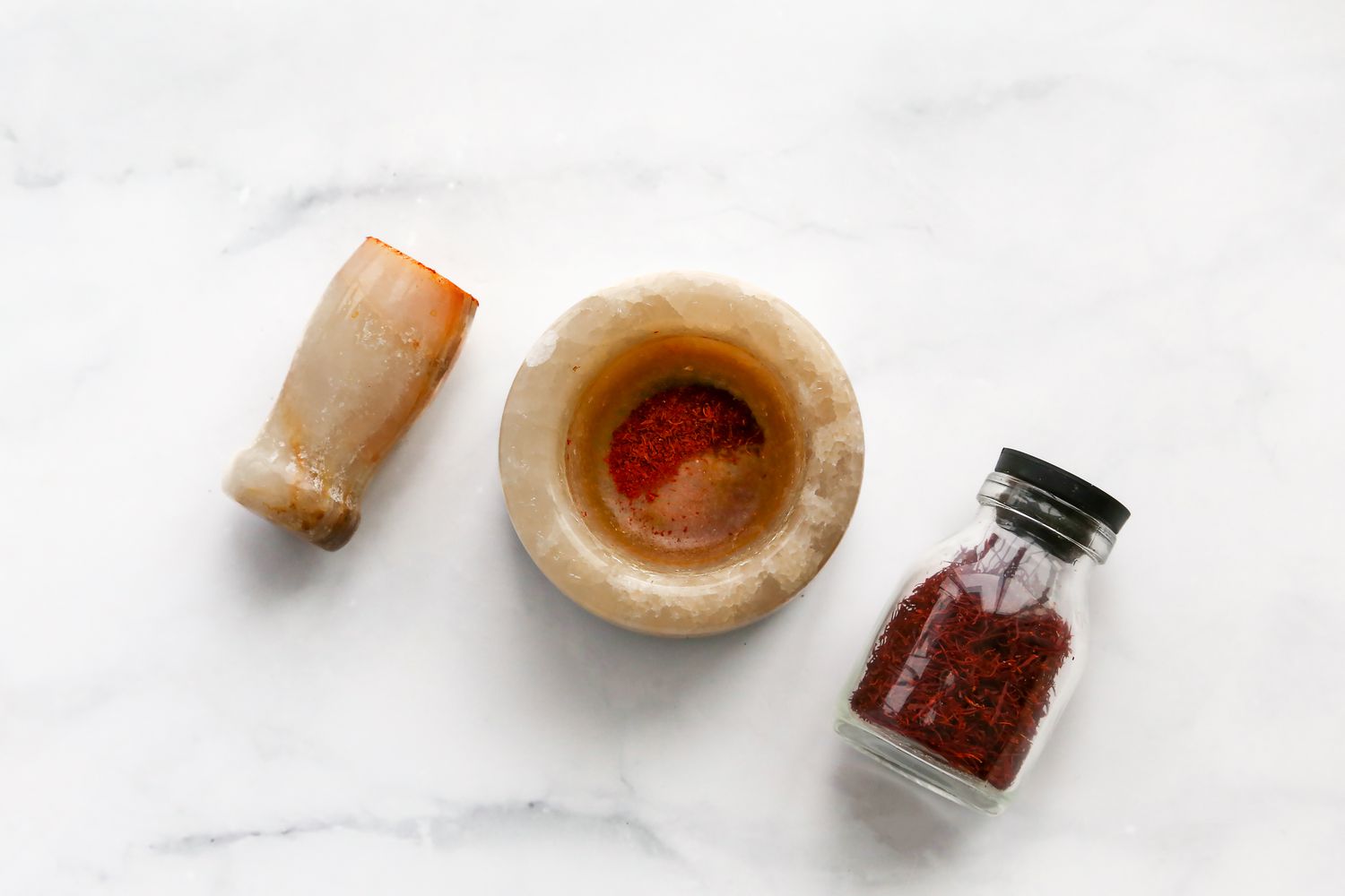 Mortar and Pestle with Finely Ground Saffron Next to a Jar with More Saffron