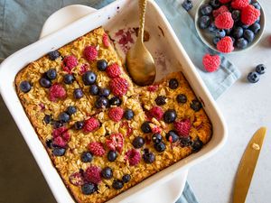 Overhead view of a baking pan with Baked Berry Oatmeal topped with extra berries with a serving removed from the dish.