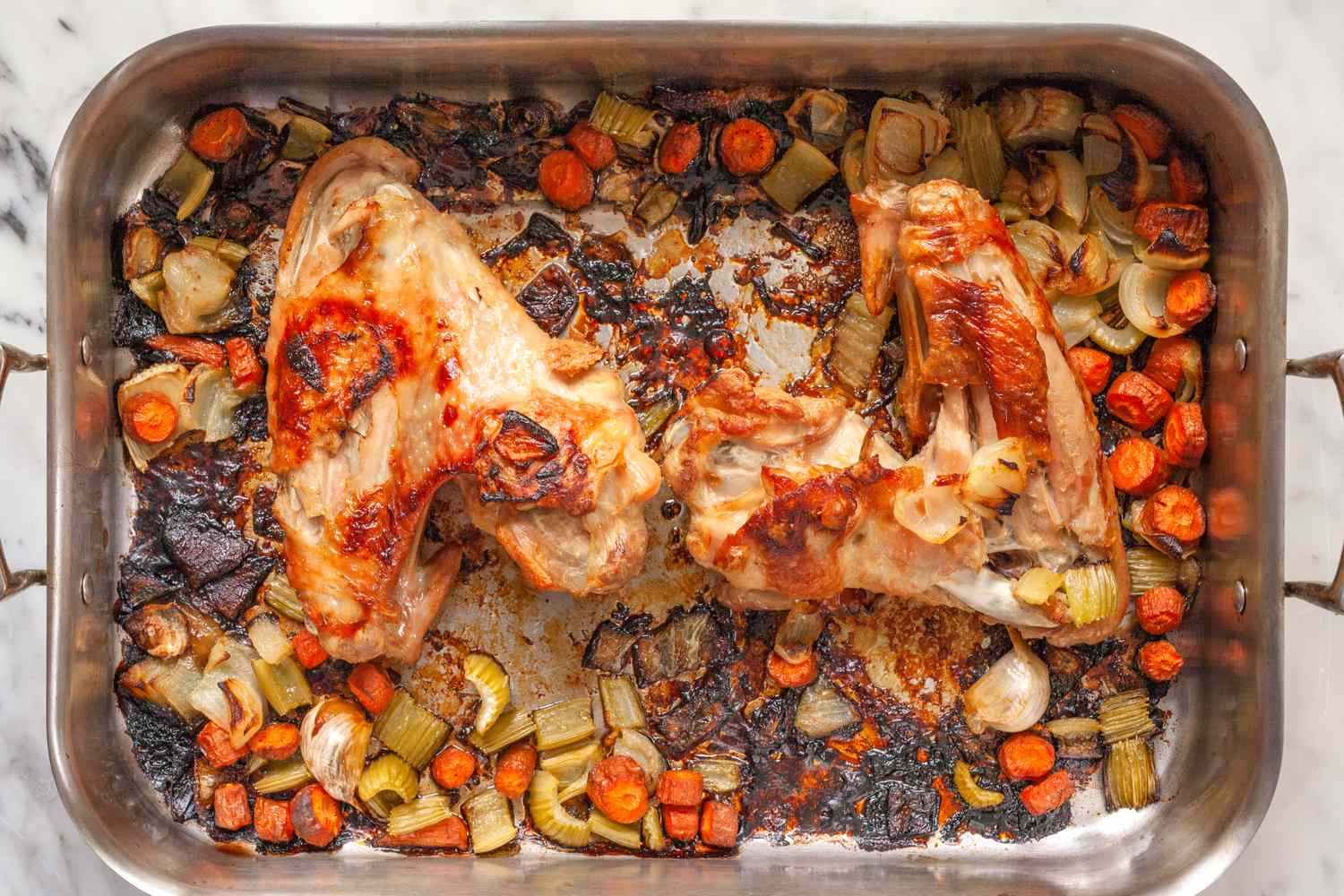 Roasted turkey pieces atop vegetables in a roasting pan
