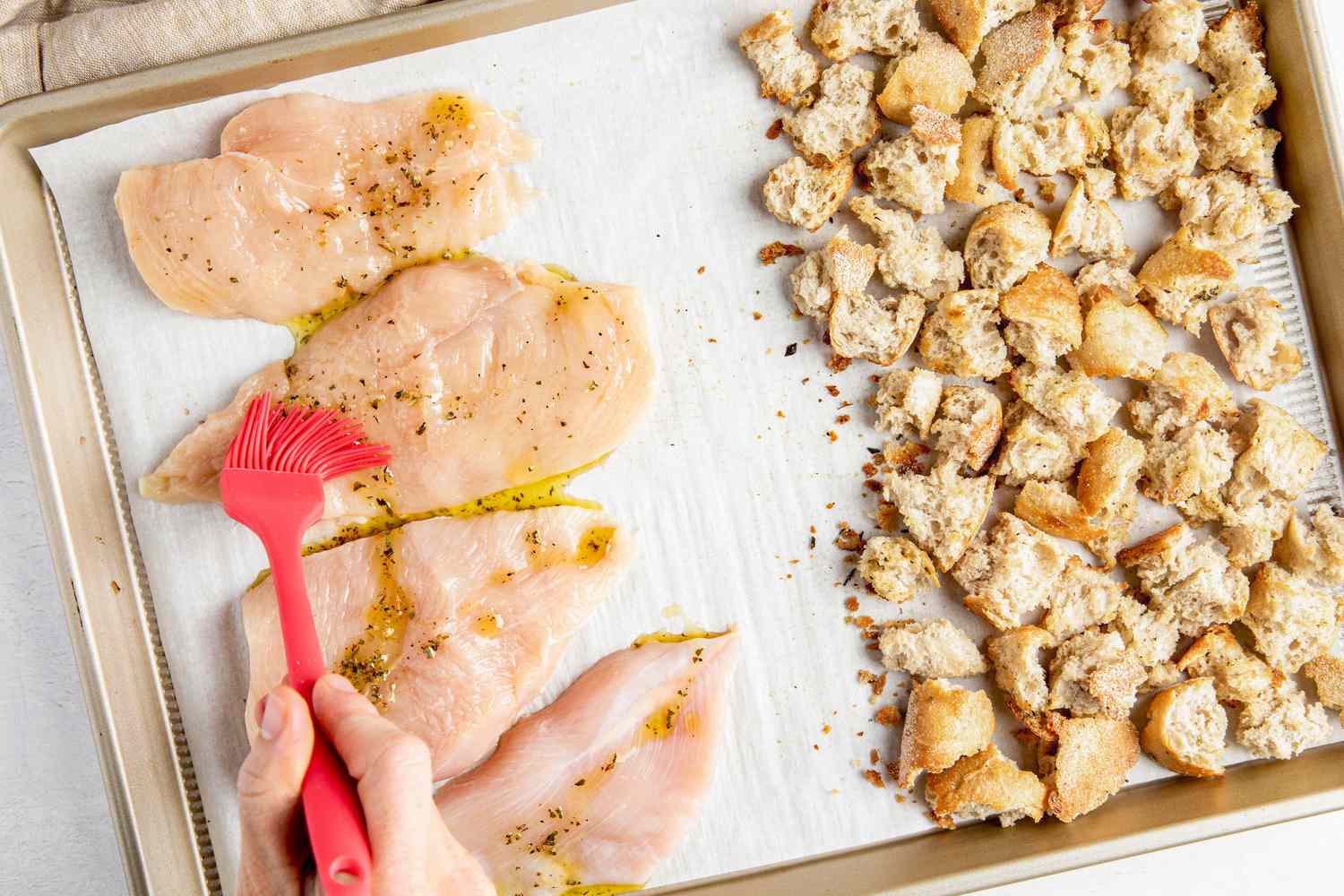 On the baking sheet (L to R): seasoning brushed onto some chicken breast and seasoned croutons