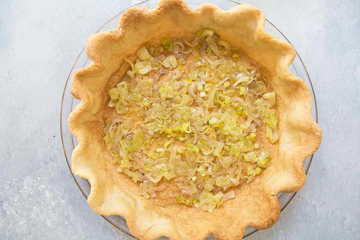 Tomato quiche spread cooked shallots over the bottom of the pre-baked pie shell