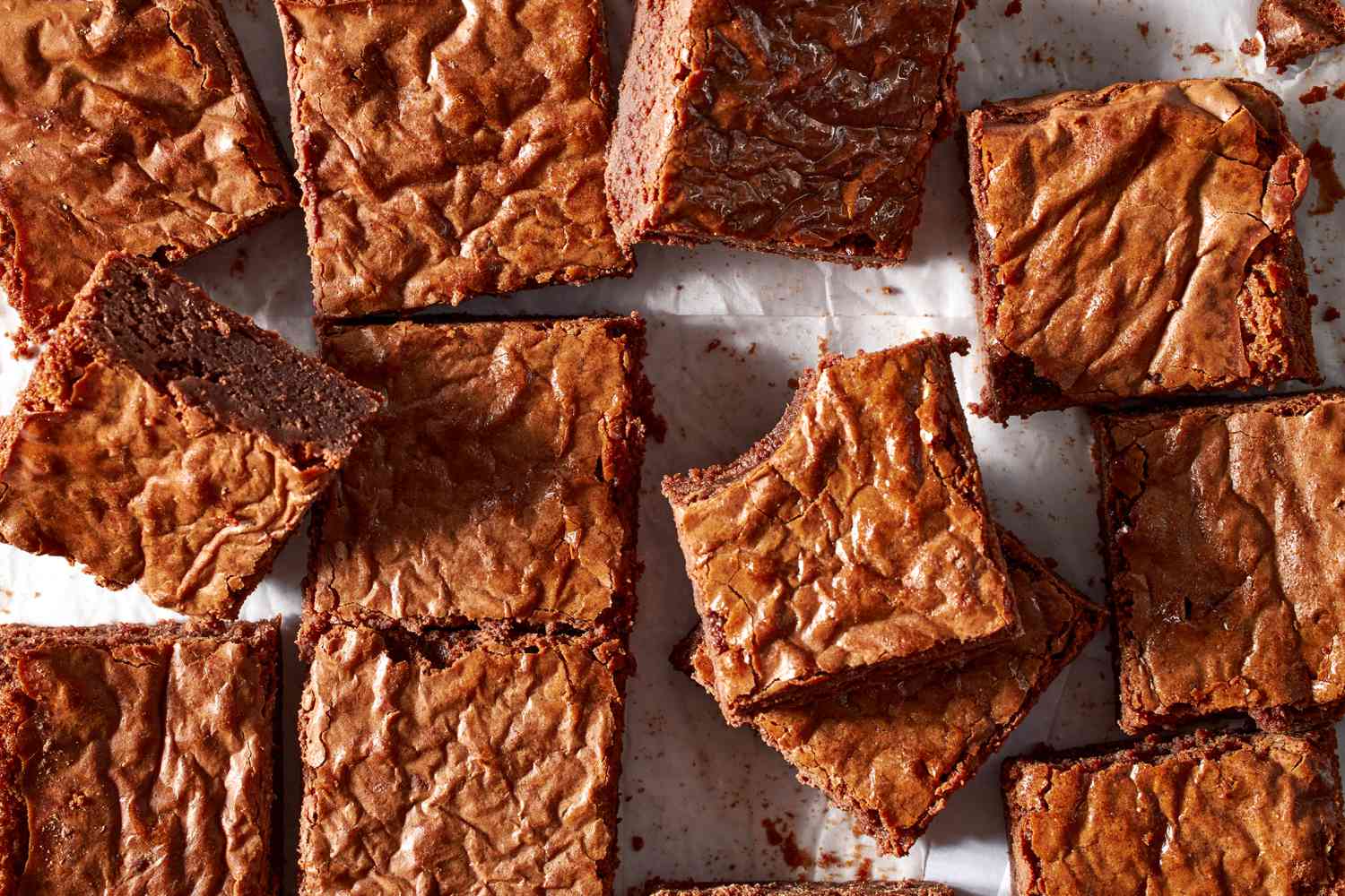 Sliced brownies laying on parchment paper with a bite taken out of one