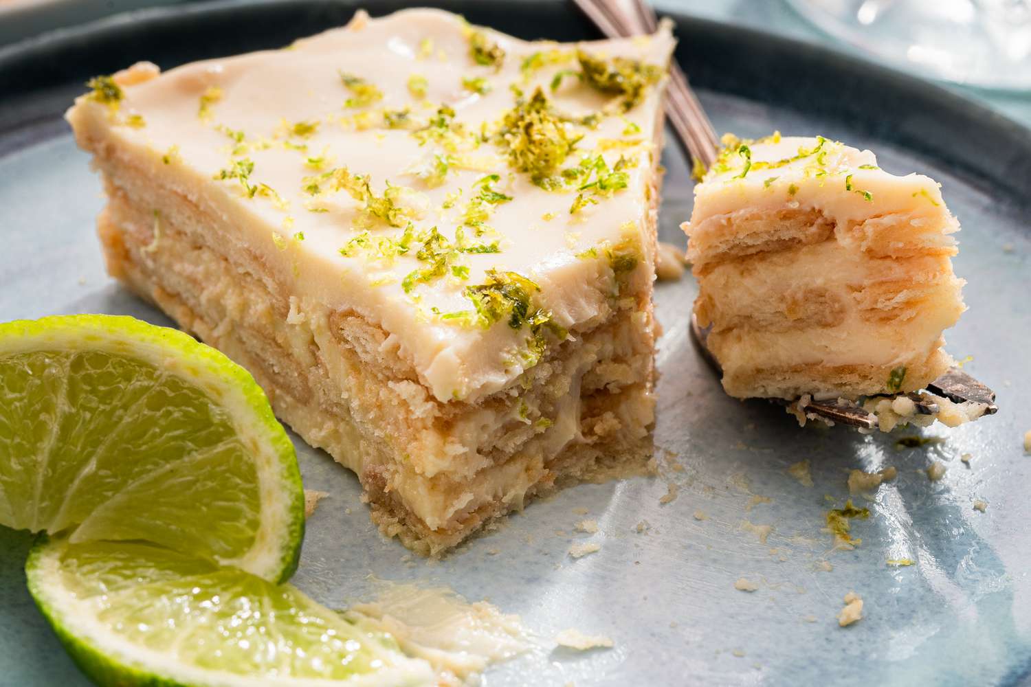 Layered dessert served with a fork and garnished with lime slices, focus on texture and freshness