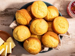 Nothin' muffins in a table napkin lined-bowl next to a bowl of butter and a jar of jam 