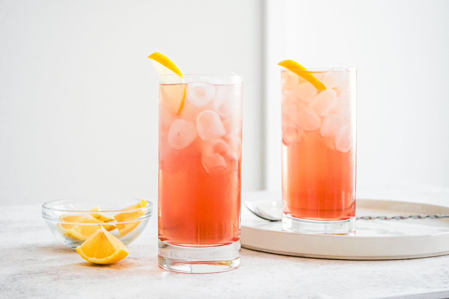 Glasses of Sloe Gin Fizz with Ice and Lemon Slices with Bowl of Lemon Wedges 