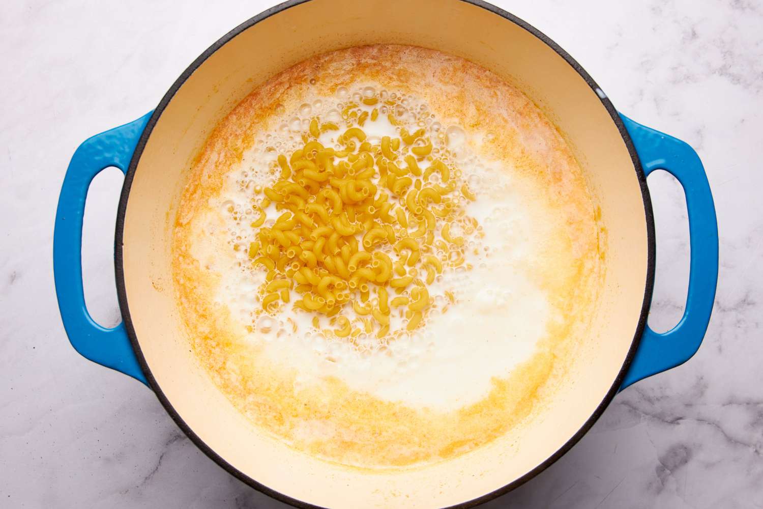 Macaroni pasta added to the dutch oven for one pot mac & cheese recipe