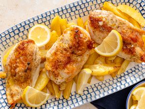 Greek-Style Lemon Chicken and Potatoes on a platter garnished with lemons