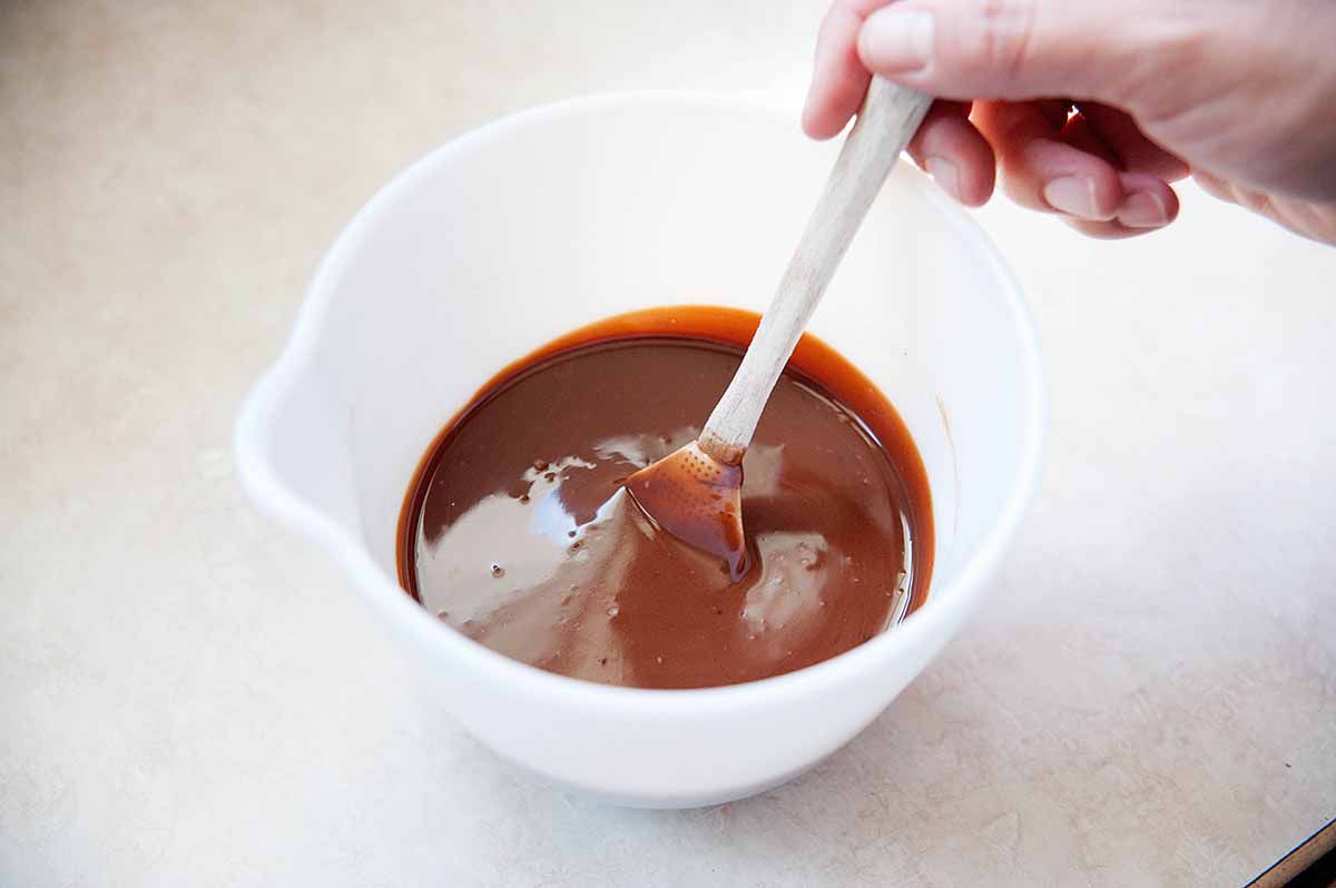 Stirring together melted chocolate and heavy cream.