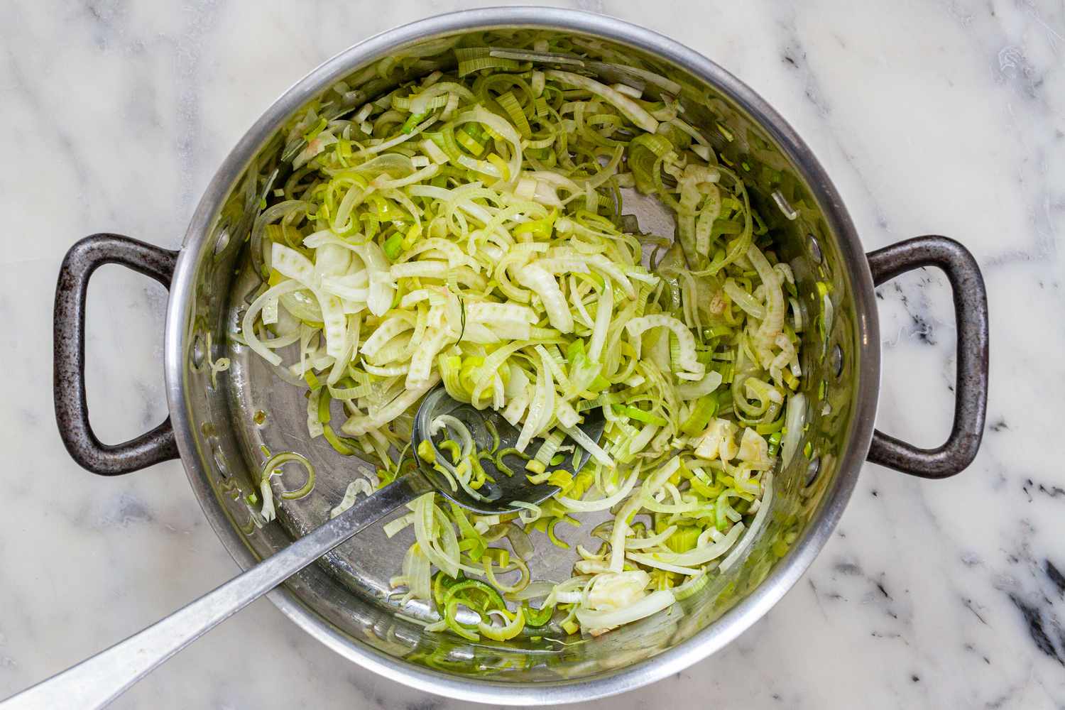 Sauteeing aromatics in a stockpot for a bouillabaise recipe.