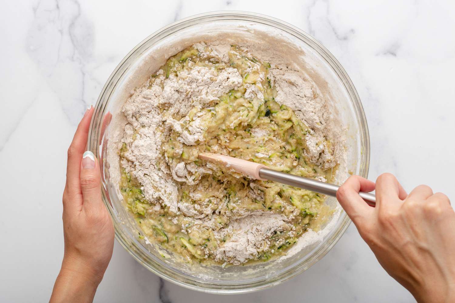 Zucchini mixture and flour mixture being stirred together with a spatula 