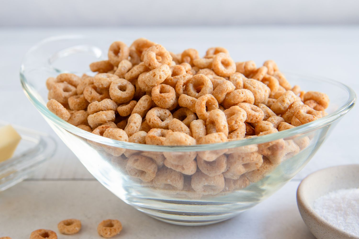 A bowl of fried Cheerios with butter and salt visible in the background