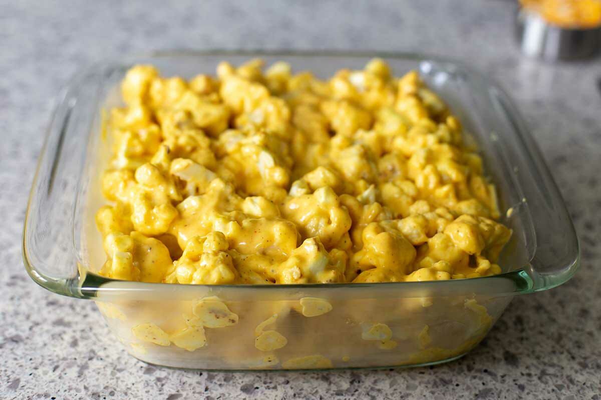 Melted cheese covers cauliflower in a glass casserole dish to make the Best Cheesy Cauliflower.