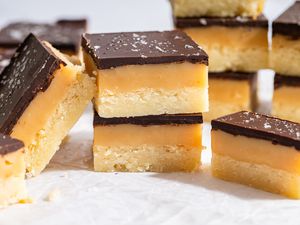 Closeup view of a stack of Millionaire Shortbread bars on parchment paper with several bars visible in the background