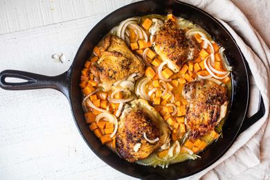 apple cider braised chicken thighs with sweet potatoes in black cast iron skillet