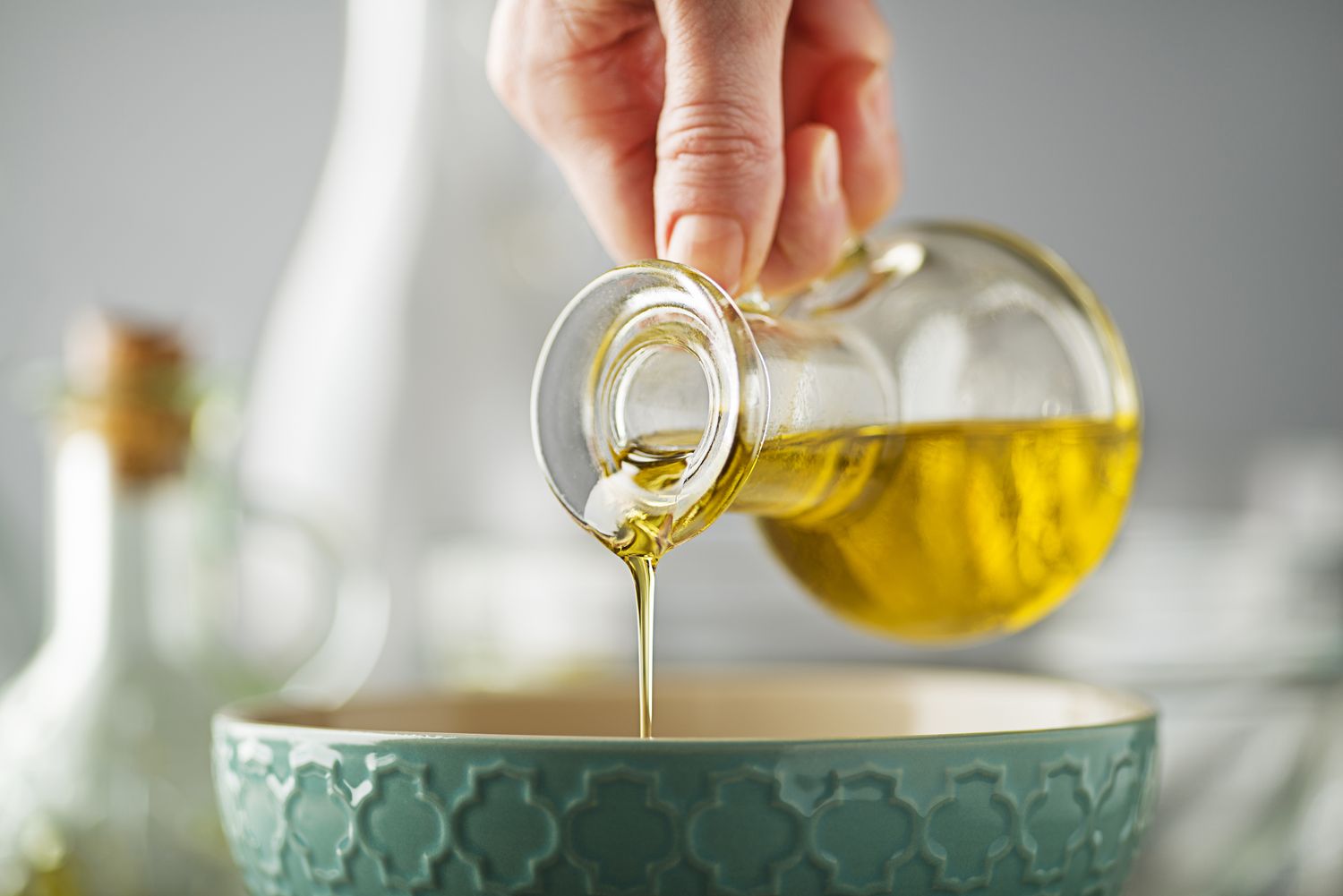 Pouring olive oil from a small bottle into a ceramic bowl