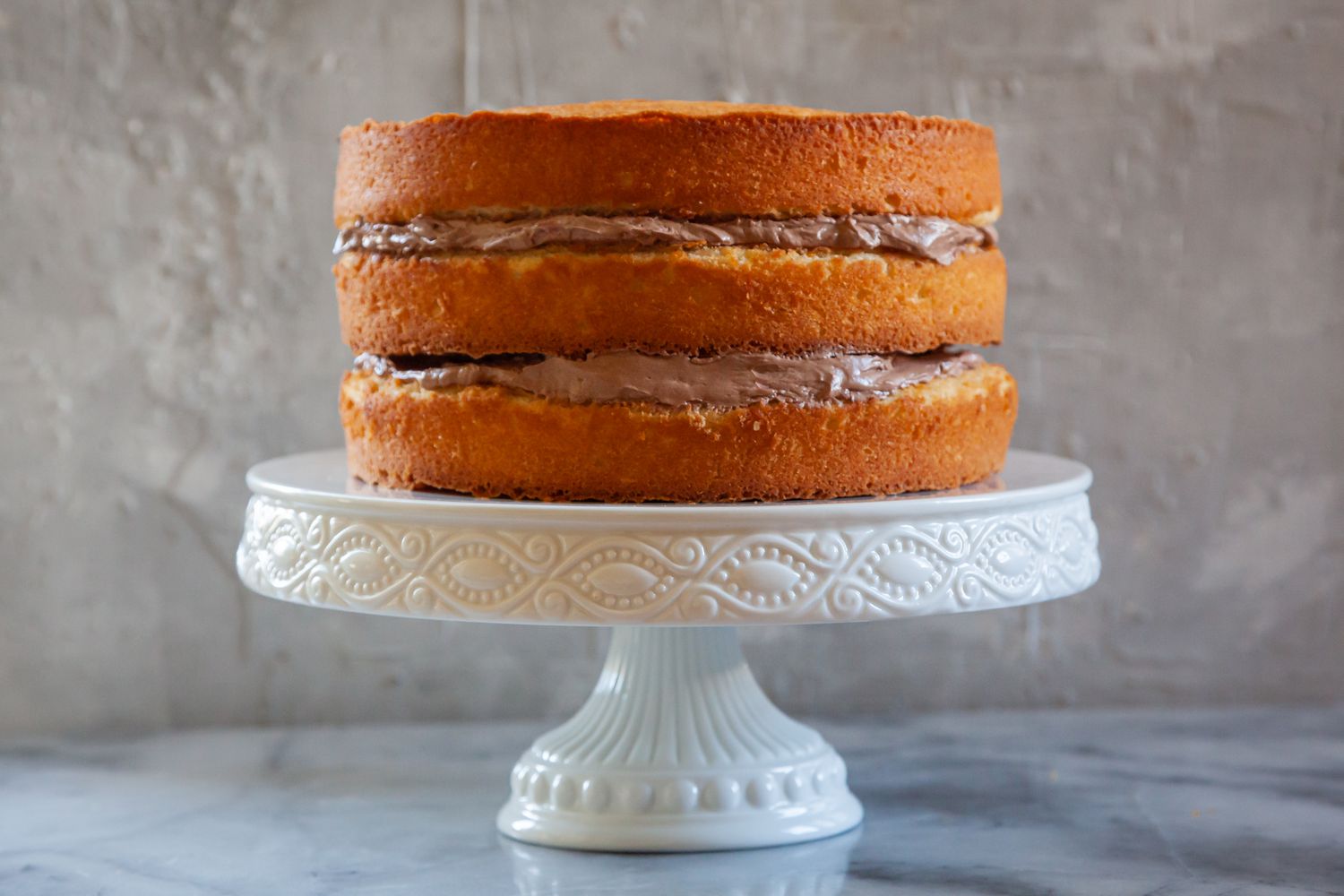 Secrets for the perfect layer cake with a three layer cake on a cake stand.