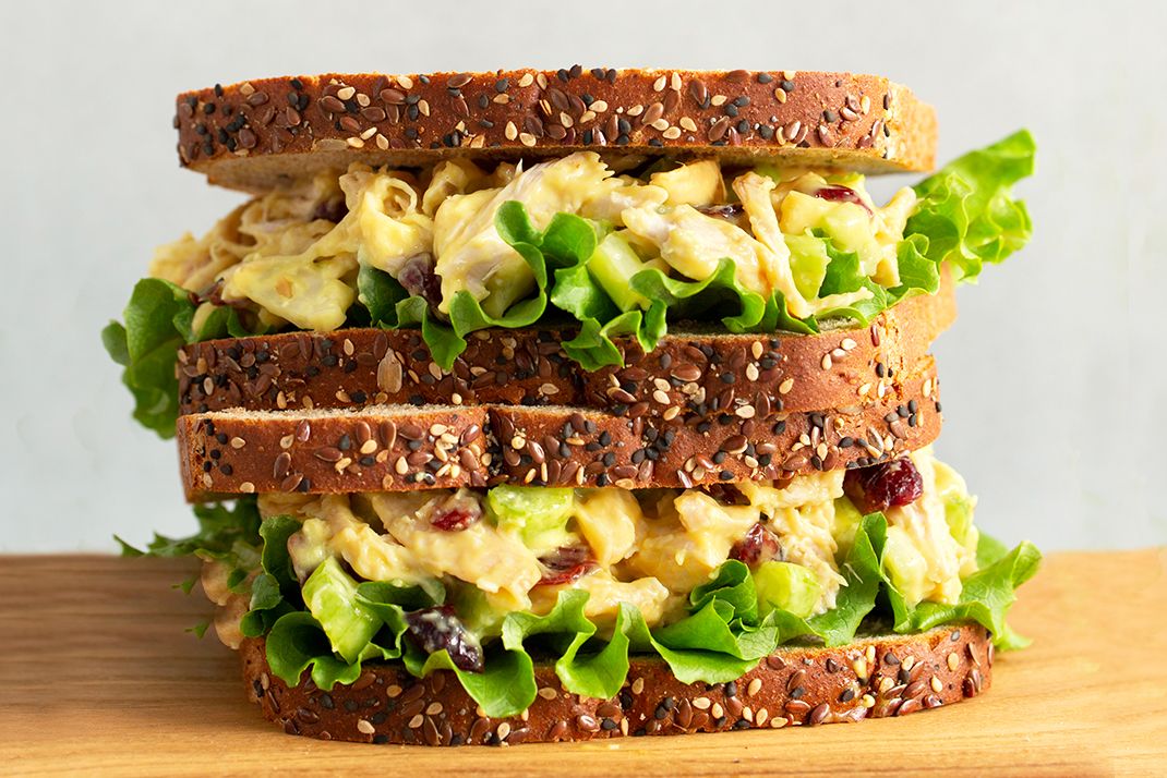 Triplelayered sandwich made with seeded bread lettuce and a creamy filling placed on a wooden surface