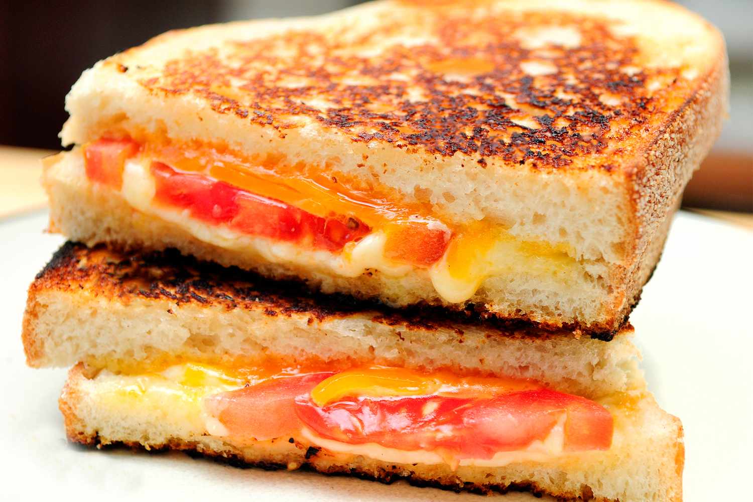 Grilled cheese sandwich with tomato slices visible between melted cheese and toasted bread