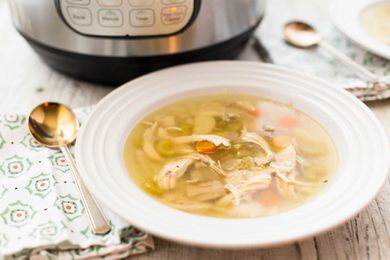 Instant pot chicken noodle soup in a bowl with the instant pot in partial view behind it.