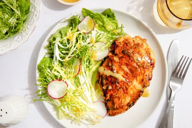 Chicken dinner on a plate with a side salad at a table setting