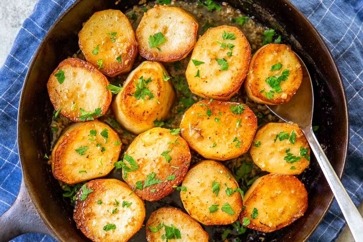 Skillet filled with garlic melting potatoes topped with parsley