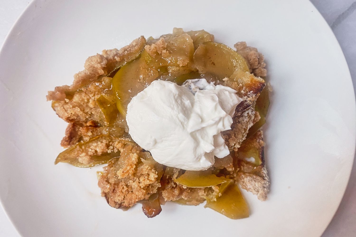 Apple crumble served on a plate with a dollop of whipped cream
