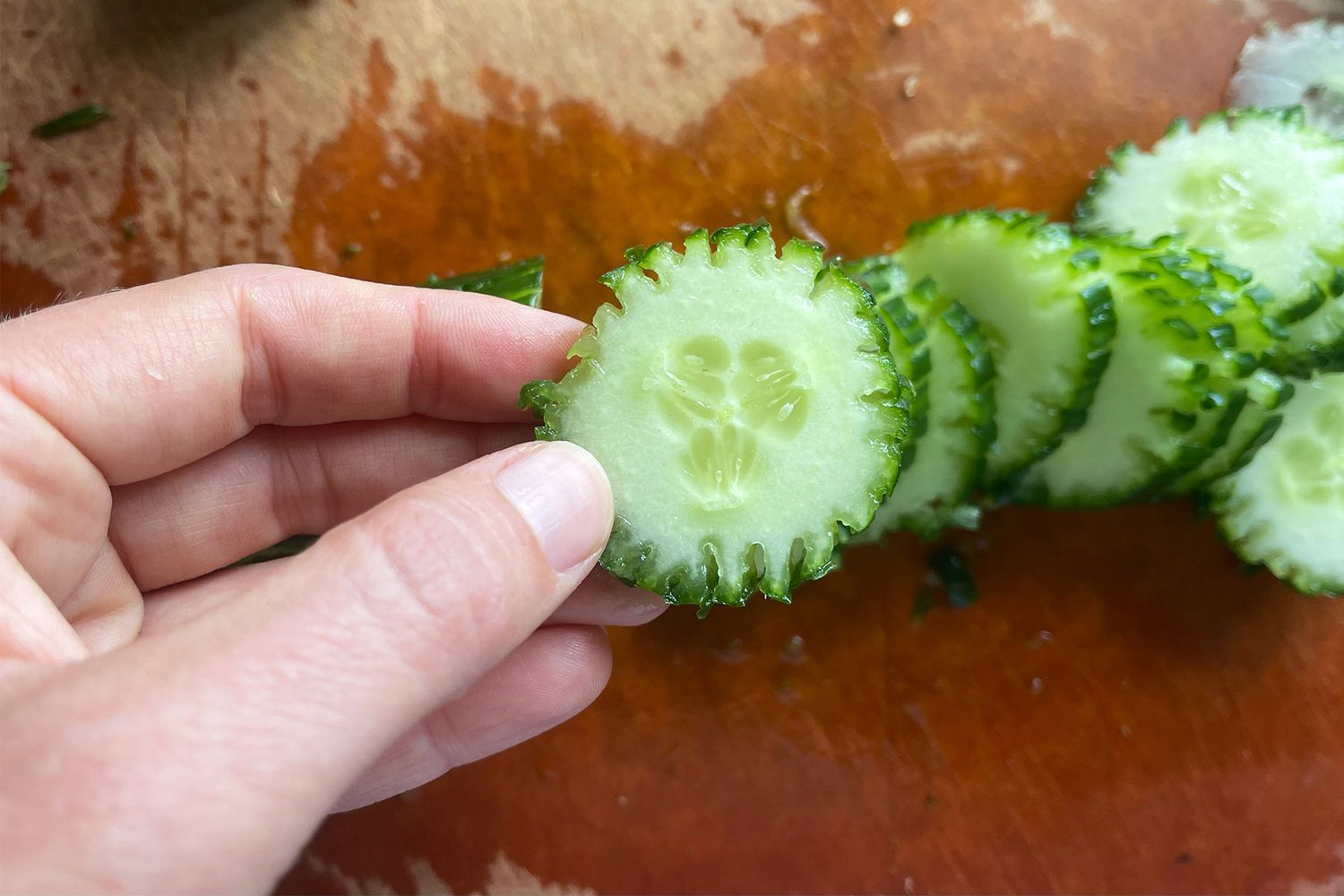 Sliced cucumbers with a decorative edge held by a hand
