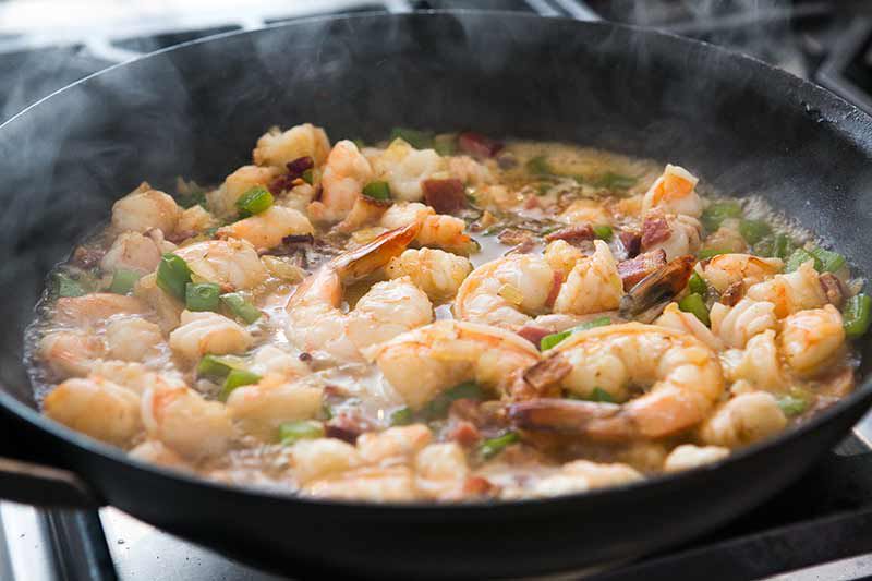 adding stock to shrimp in pan