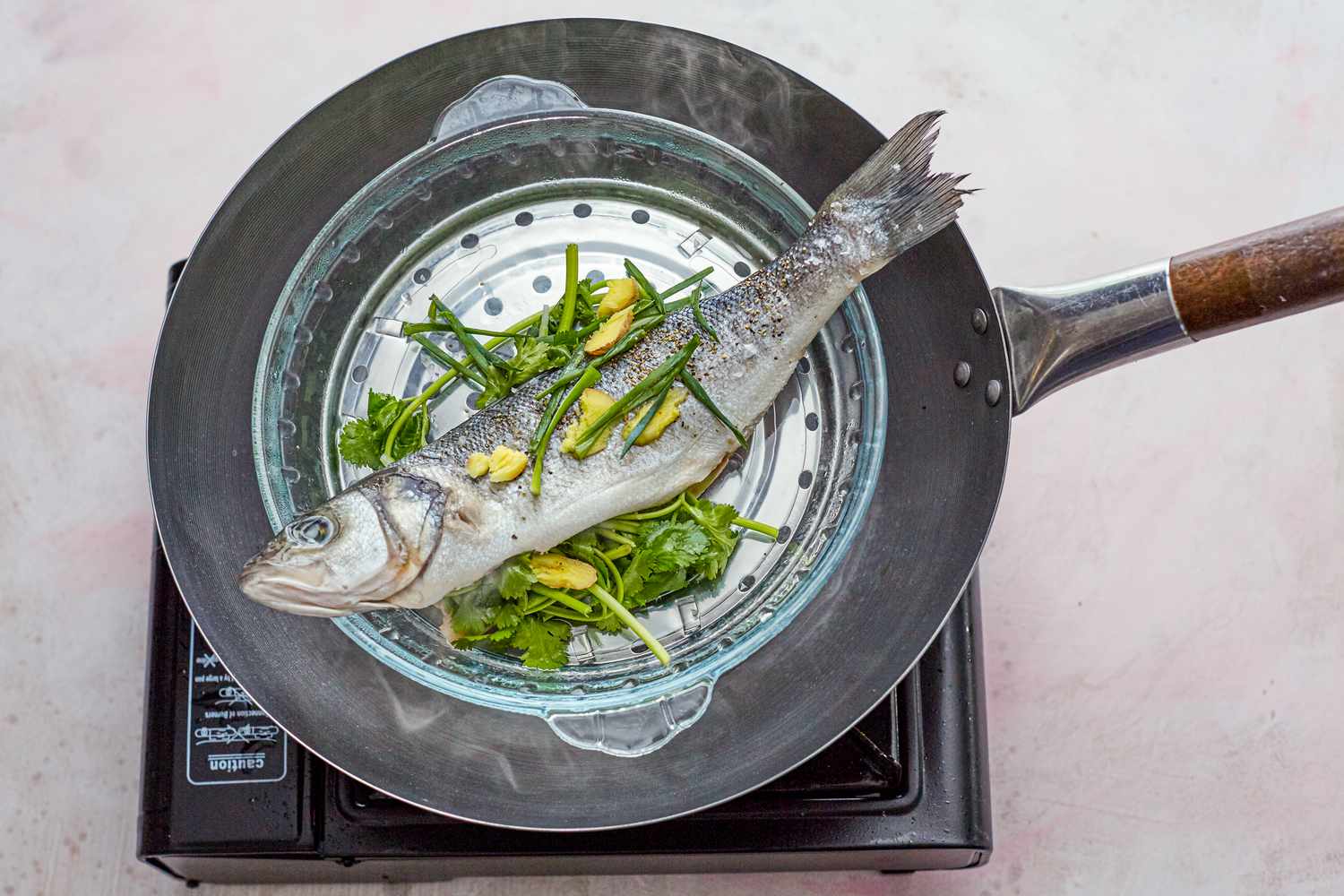 Whole steamed fish with ginger and scallions steamed in a wok.