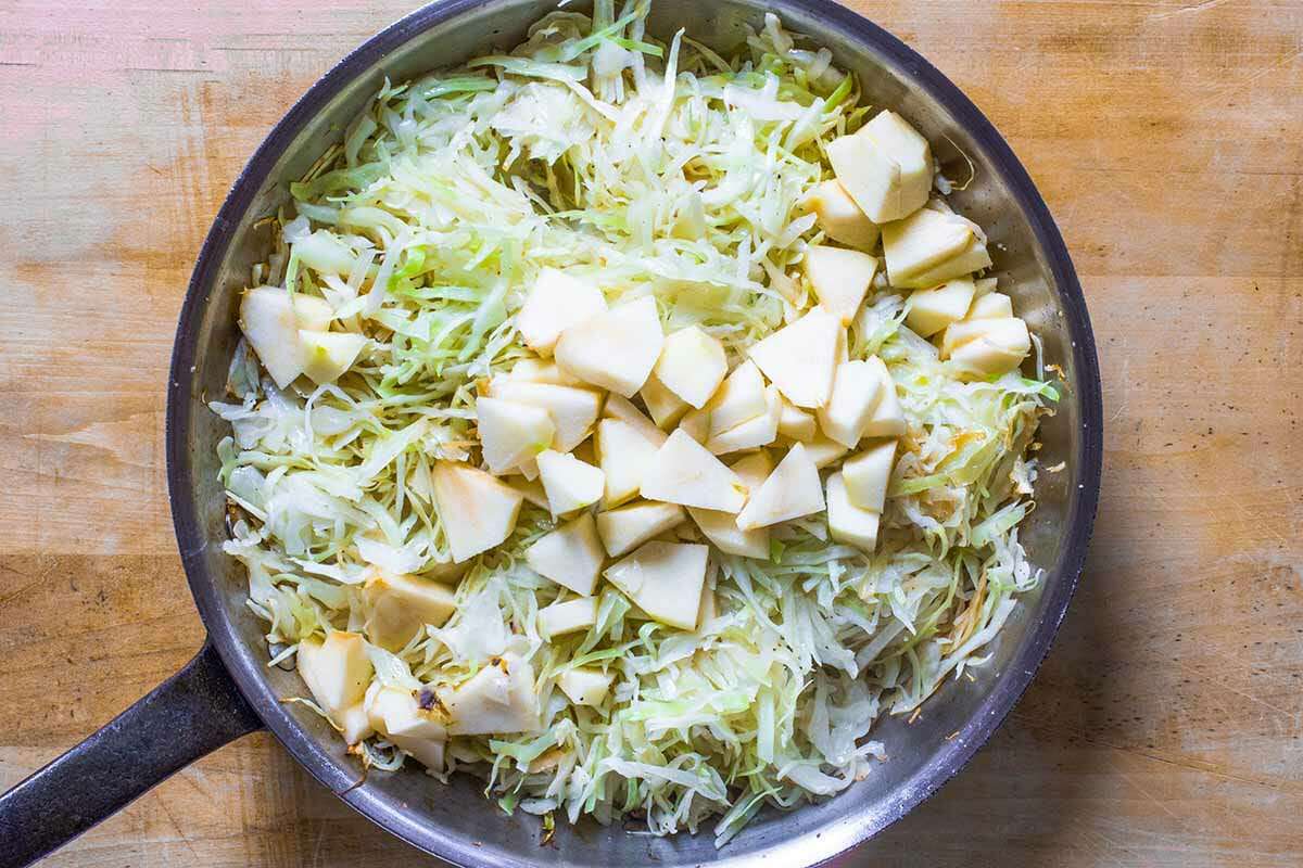 Cooked cabbage in a skillet with apple on top