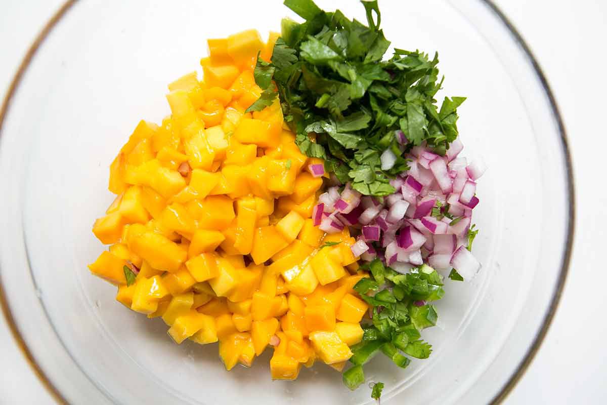 Ingredients for mango salsa resting in a glass bowl