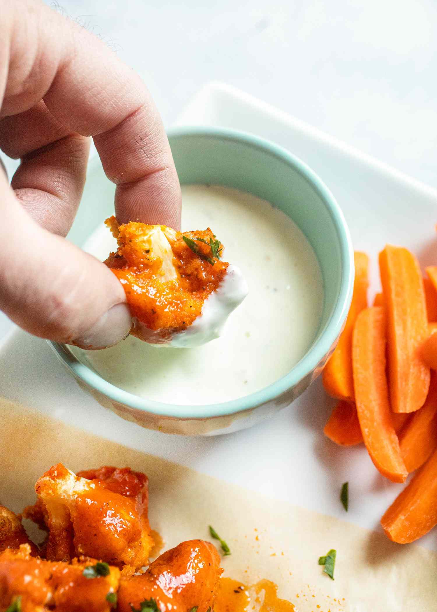 Dipping Air Fryer Buffalo Cauliflower in sauce.
