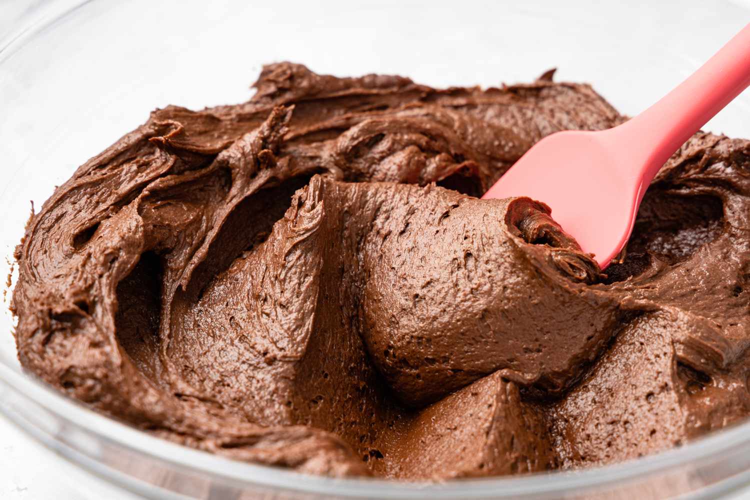 Bowl of Easy Chocolate Buttercream Frosting With a Rubber Spatula