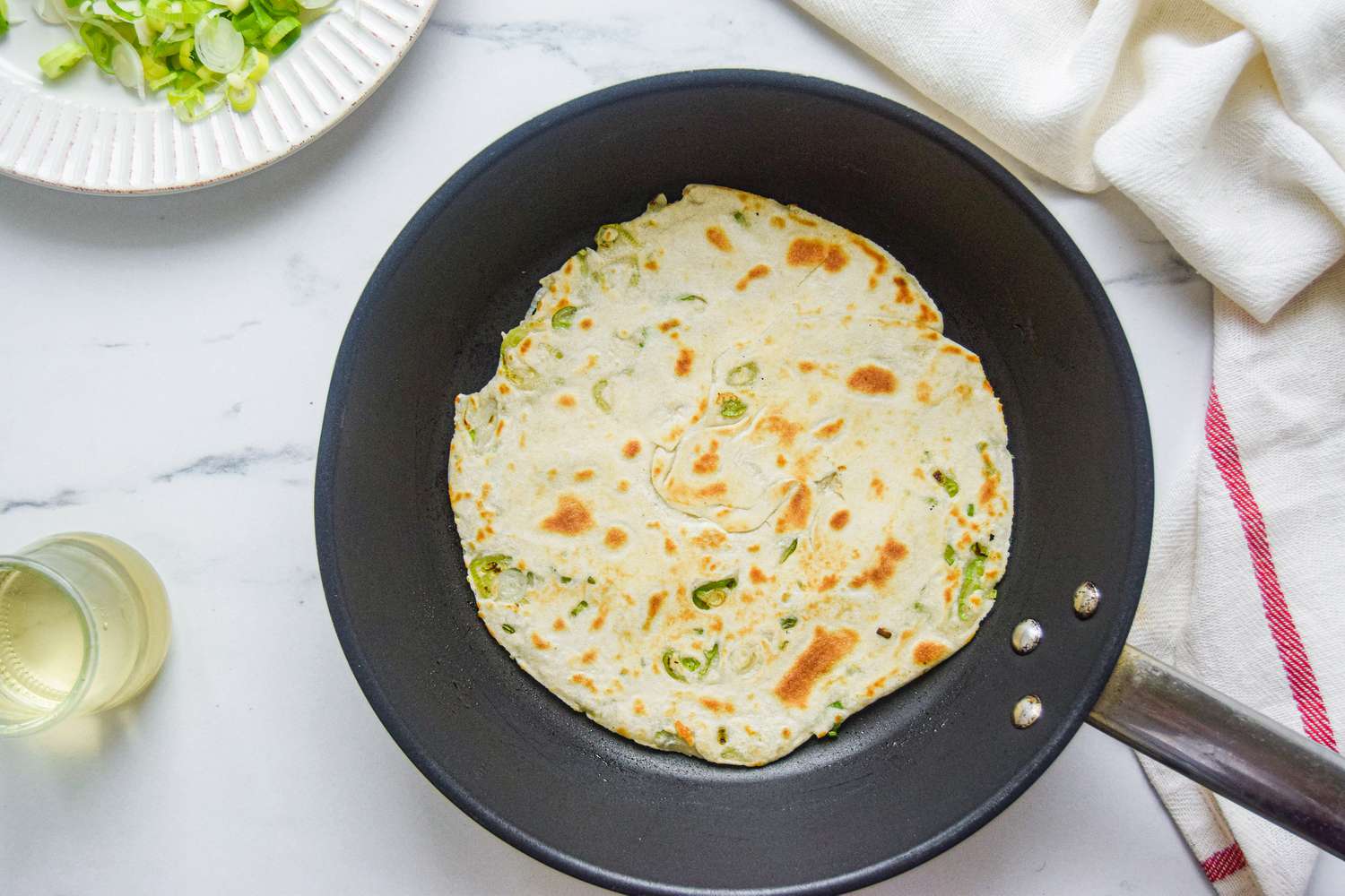 Frying a scallion pancake in a skillet.