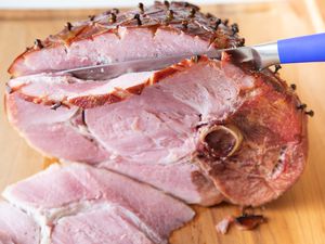 How to cook ham in the oven and slice it on a cutting board.