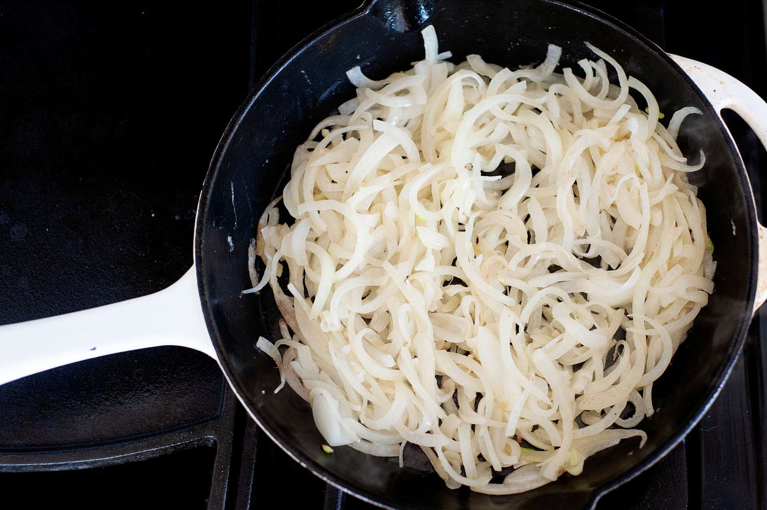 Sliced onions cooking in a skillet to make a liver and onions recipe.
