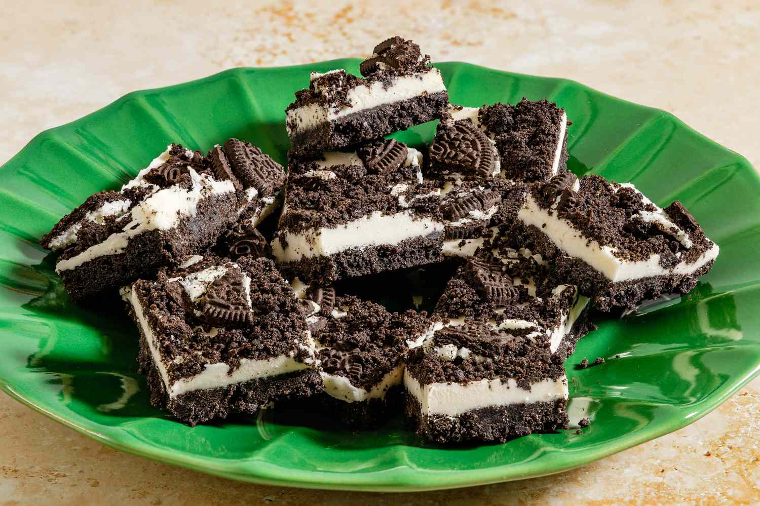 A green plate with a stack of Oreo dessert bars made of crushed cookies and cream filling