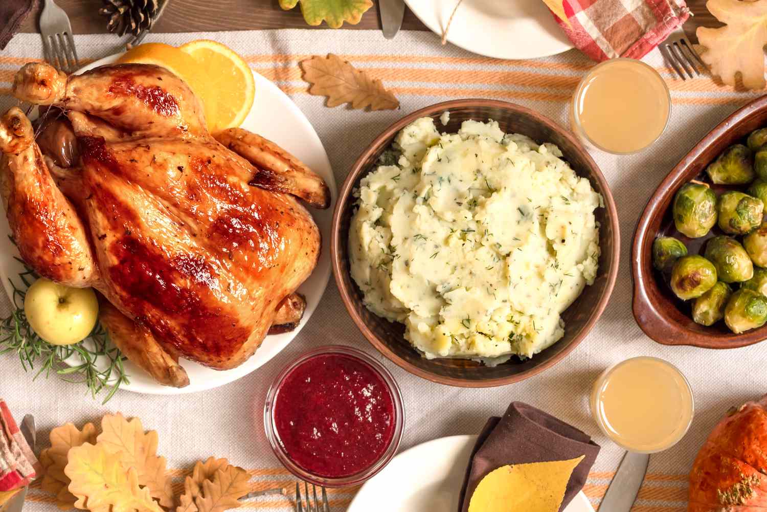 A Thanksgivingstyle meal with a roasted turkey mashed potatoes cranberry sauce and Brussels sprouts served on a decorated table