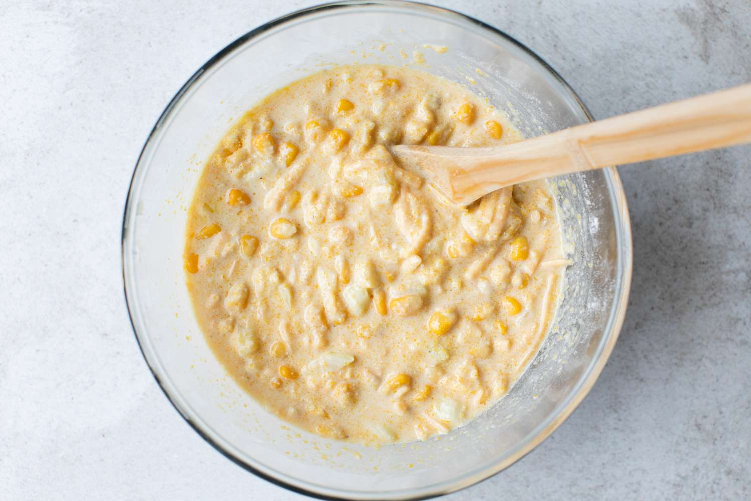 Cheesy Skillet Cornbread Batter in a Bowl with a Wooden Spoon