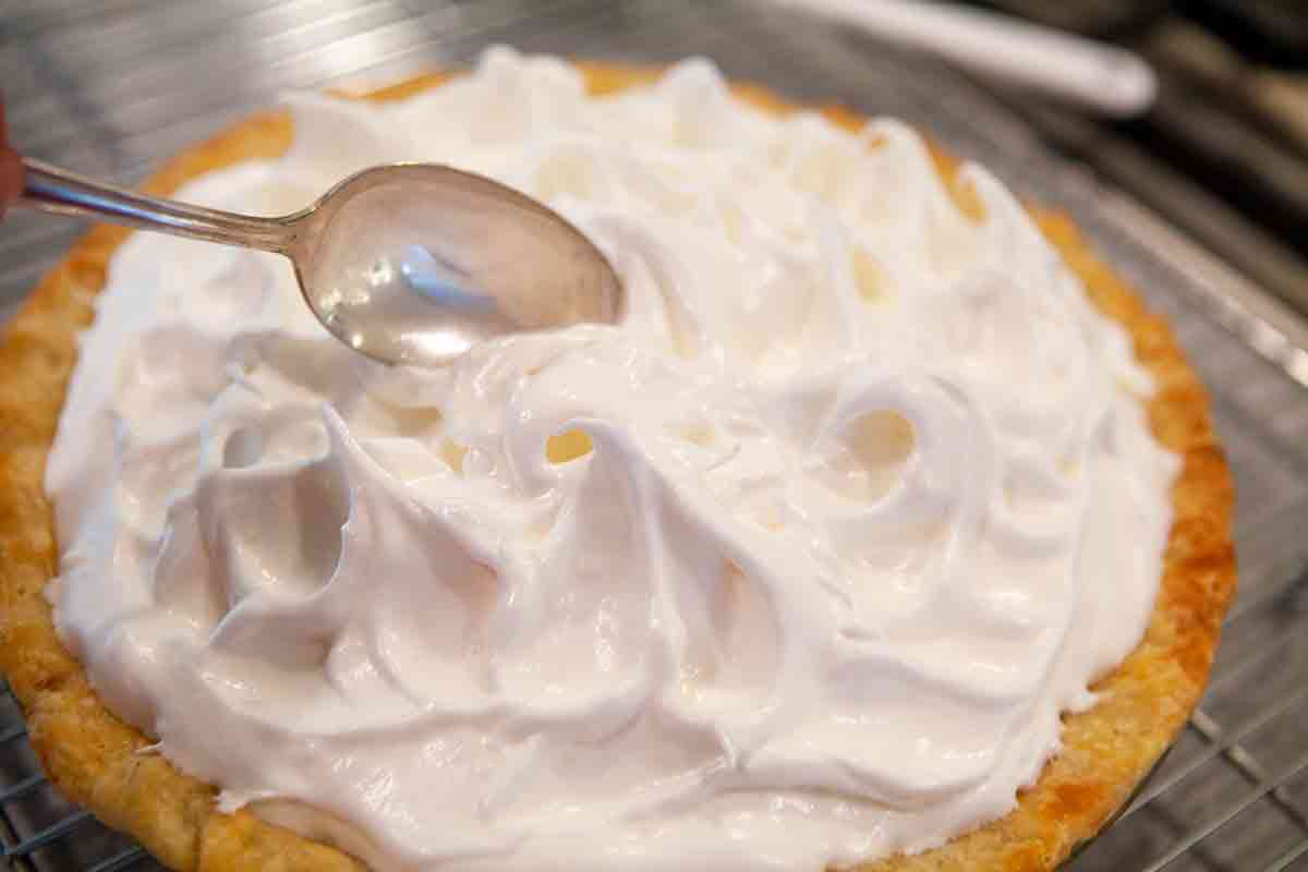 spread meringue topping over top of rhubarb filling in pie crust