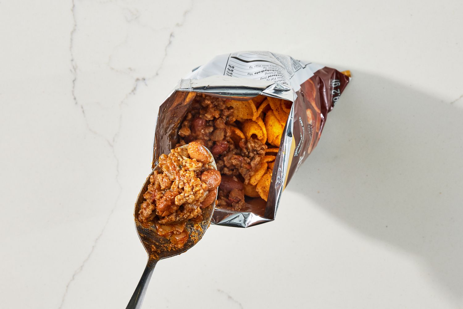 Beans and beef topping added to bag of chips for walking tacos
