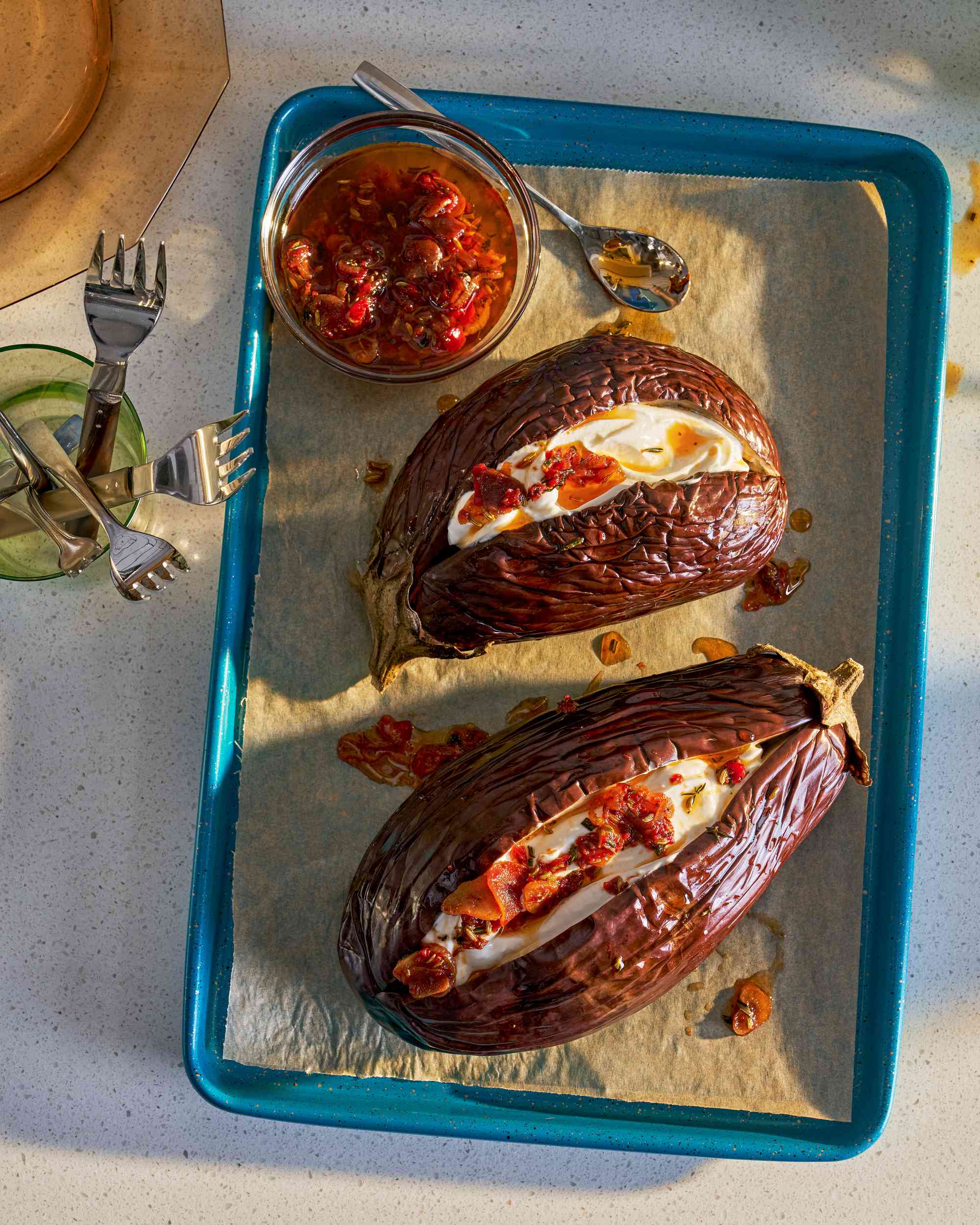 Baking sheet with two roasted eggplant topped with yogurt and chili crisp