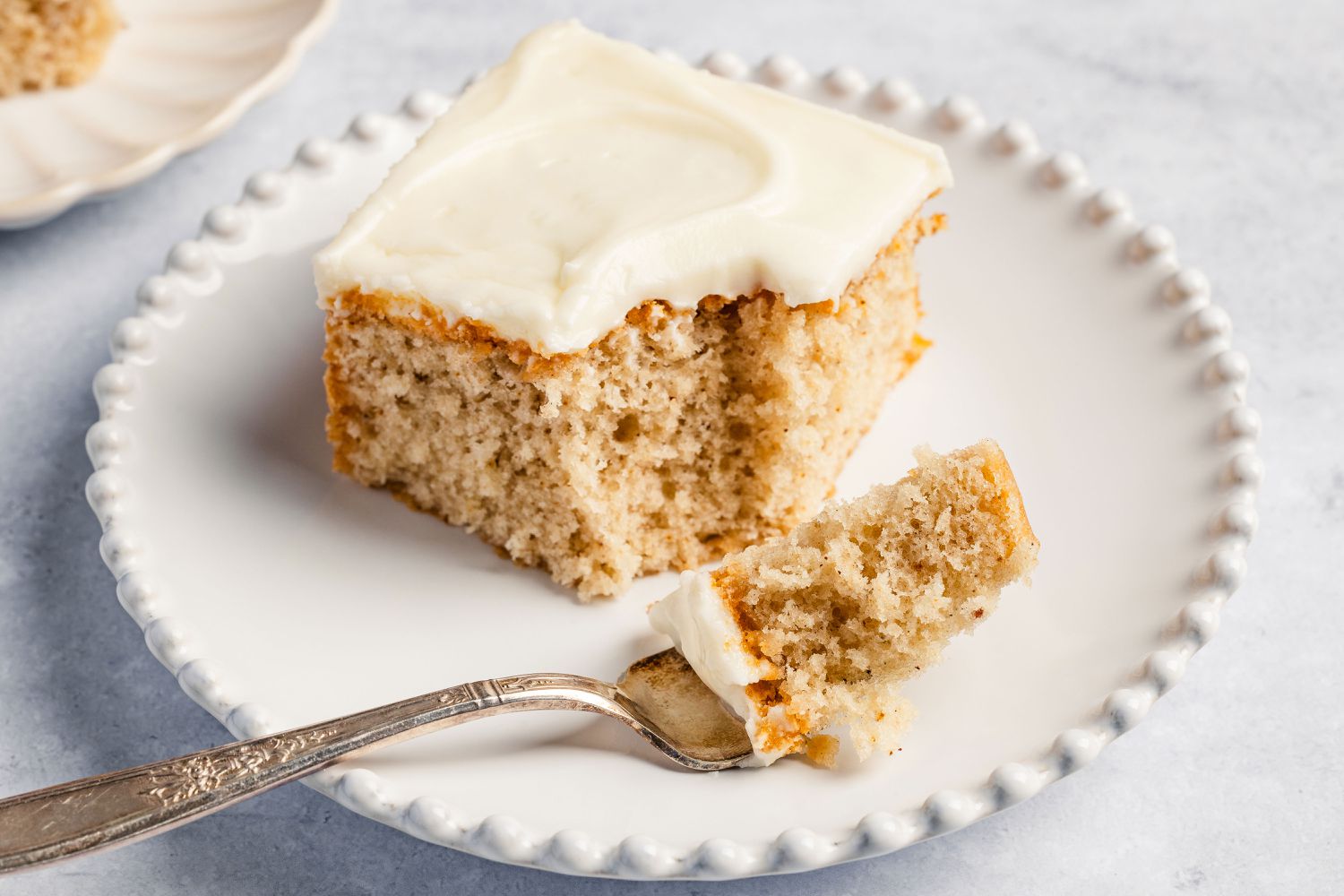square slice of Feather Cake on a plate with a fork with a small bite portion on it