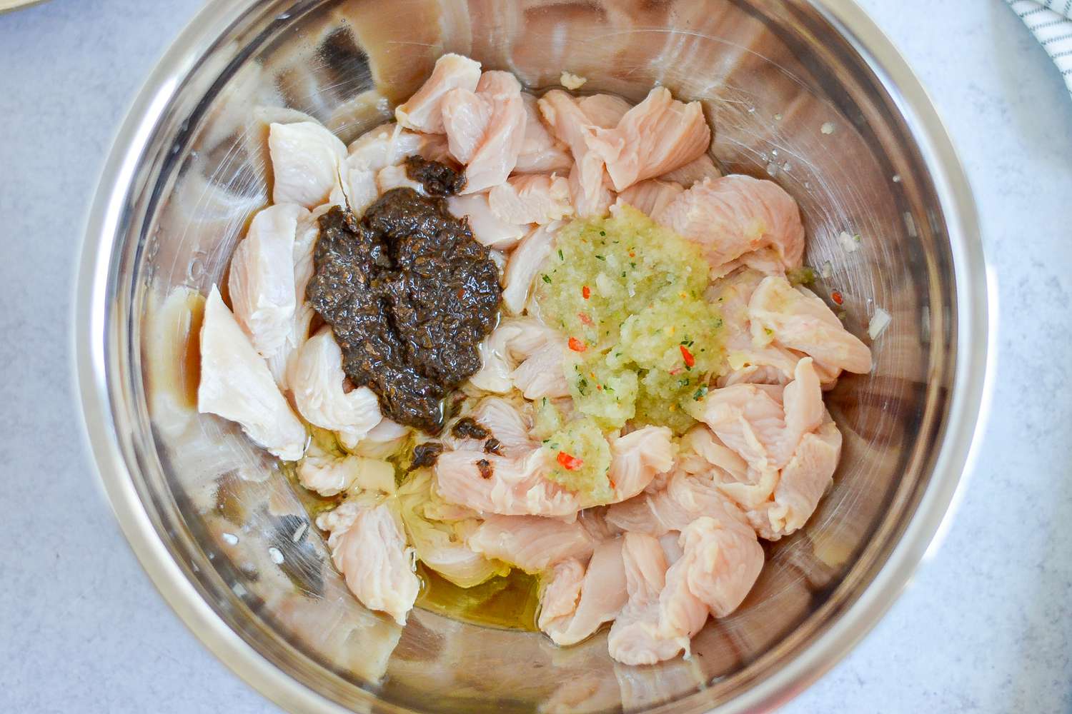 Seasoning Added to Chicken in Large Bowl for Rasta Pasta with Jerk Chicken